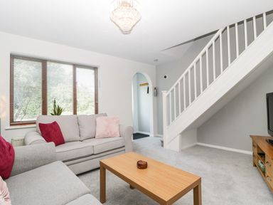 A living room with two sofas a wooden coffee table a TV stand under stairs and window blinds at 16 Mythern Meadow in Bradford-On-Avon