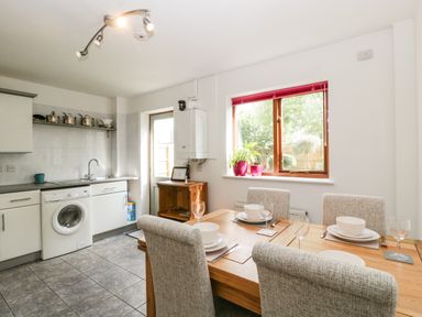 A kitchen with a dining table set for four next to a window with plants at 16 Mythern Meadow in Bradford-On-Avon