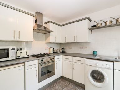 A kitchen with white cabinets a microwave toaster oven washing machine and utensils at 16 Mythern Meadow Bradford-On-Avon