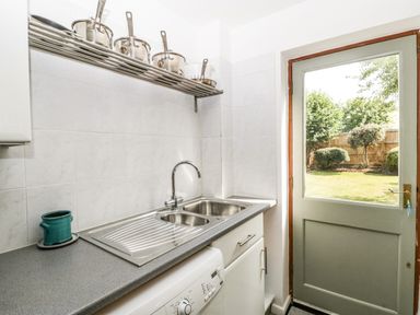 A kitchen sink with pots on a rack above and a door leading to a garden at 16 Mythern Meadow Bradford-On-Avon