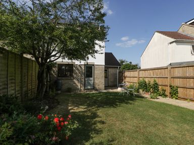 A backyard garden with a tree flowers and a small table with chairs at 16 Mythern Meadow in Bradford-On-Avon
