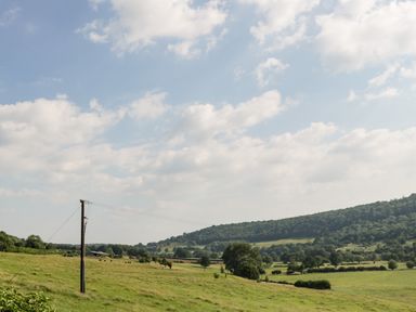 A rural landscape with green fields trees hills and a power line at 16 Mythern Meadow in Bradford-On-Avon