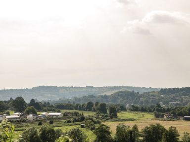A rural landscape with fields trees and houses under a cloudy sky at 16 Mythern Meadow in Bradford-On-Avon
