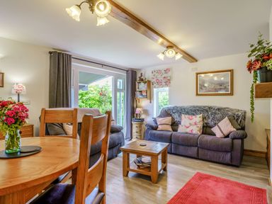 A living room with wooden dining table and chairs two gray sofas with cushions small wooden coffee table and plants at Kavieng in Glangrwyney near Gilwern