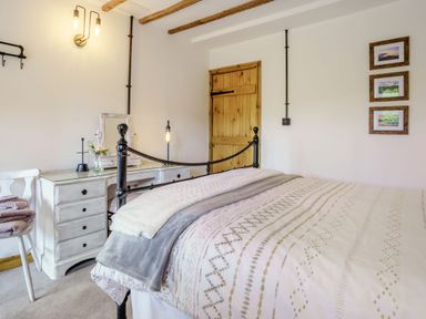 A bedroom with a bed and a white dresser with a mirror and chair at Kavieng in Glangrwyney near Gilwern
