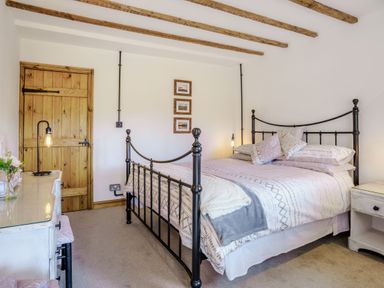 A bedroom with a black metal bed frame and wooden ceiling beams at Kavieng in Glangrwyney near Gilwern