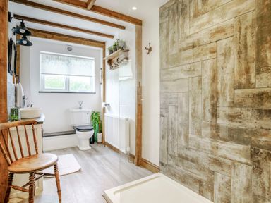 A bathroom with a wooden chair sink toilet shower area and window at Kavieng Glangrwyney near Gilwern