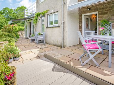 A patio area with stone flooring and outdoor chairs with pink cushions at Kavieng in Glangrwyney near Gilwern
