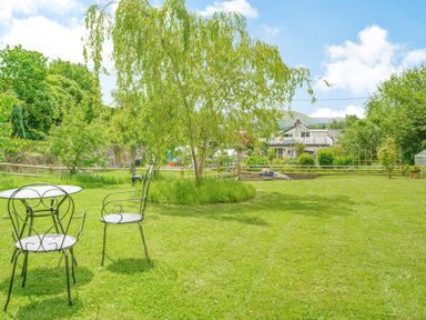 A garden with metal chairs and table on grass near a tree and houses in the background at Kavieng Glangrwyney near Gilwern