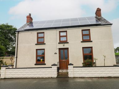A two-story house with solar panels on the roof and a front gate at Brynawel in Llangynin near Llanboidy