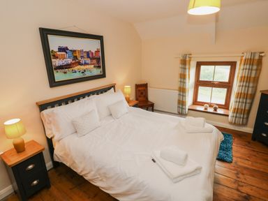 A bedroom with a double bed side tables lamps a framed picture and a window with curtains at Brynawel in Llangynin near Llanboidy