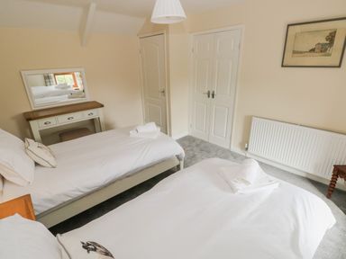 A bedroom with two single beds a dressing table with a mirror a radiator and a framed picture on the wall at Brynawel in Llangynin near Llanboidy