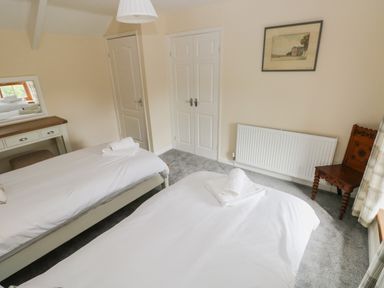 A bedroom with two beds white bedding a dressing table a mirror wooden chair and a framed picture on the wall at Brynawel in Llangynin near Llanboidy