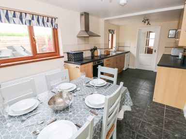 A kitchen with a dining table set for four and wooden cabinets at Brynawel in Llangynin near Llanboidy