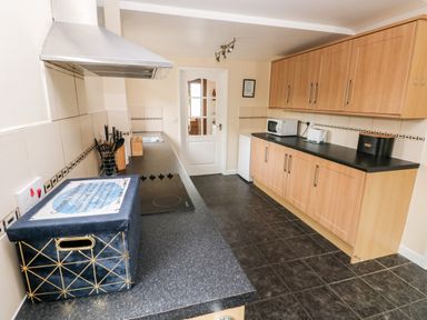 A kitchen with wooden cabinets black countertops and a glass door at Brynawel in Llangynin near Llanboidy