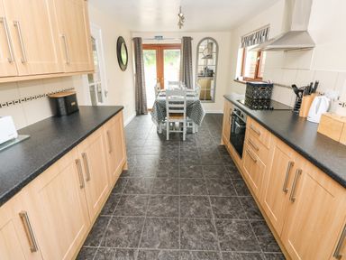 A kitchen with wood cabinets black countertops dining table and chairs at Brynawel in Llangynin near Llanboidy