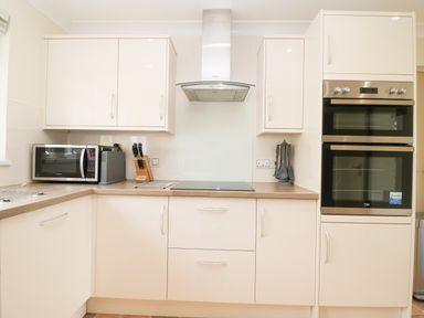 A kitchen with cabinets a microwave a knife block a stovetop an extractor hood and a double oven at Rathillet in Feock near Truro