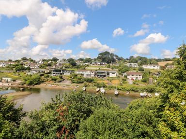 A riverside view of houses with boats moored along the shore and greenery at Rathillet Feock near Truro