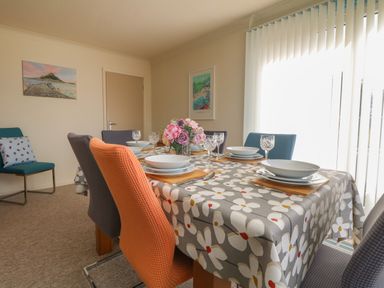 A dining room with a table set for six with plates glasses and flowers at Rathillet in Feock near Truro