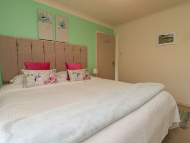 A bedroom with a double bed pink cushions and floral pillows at Rathillet in Feock near Truro