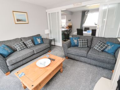 A living room with two grey sofas and a wooden coffee table at Fisherman's Row in Amble