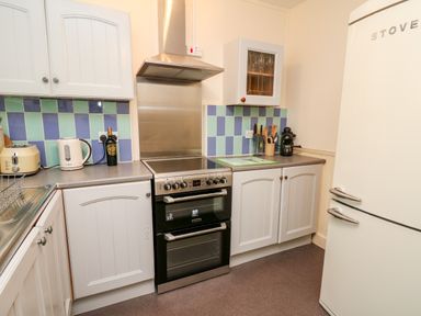 A kitchen with a stove kettle toaster and refrigerator at Myrtle Villa in Knighton