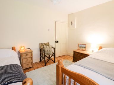 A bedroom with two single beds a wooden chair two bedside tables lamps and a framed picture at Myrtle Villa in Knighton
