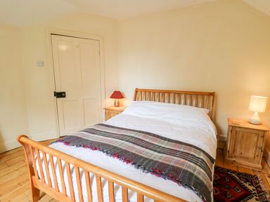 A bedroom with a wooden bed and two bedside tables with lamps at Myrtle Villa in Knighton
