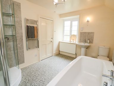 A bathroom with a bathtub sink toilet towel rack and window at Myrtle Villa in Knighton