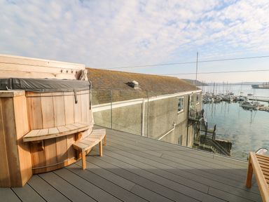 An outdoor deck with a wooden hot tub bench and a view of a waterfront with boats at 16 Arwenack Street in Falmouth