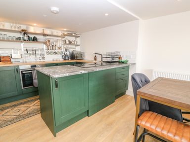 A kitchen with green cabinets a wooden dining table and mixed chairs at 16 Arwenack Street in Falmouth