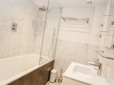 A bathroom with a bathtub shower combination a sink with a faucet a towel rack and a small trash bin at 16 Arwenack Street in Falmouth