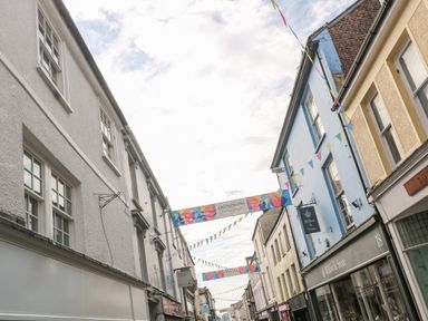 A street with white and blue buildings and hanging banners and flags at 16 Arwenack Street in Falmouth