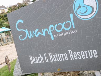 A sign for Swanpool Beach and Nature Reserve with a logo and tagline more than just a beach
