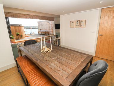 A dining area with a wooden table and chairs with a view of an outdoor patio and water at 16 Arwenack Street in Falmouth