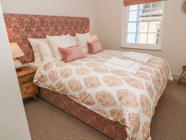 A bedroom with a double bed covered with patterned bedding and pillows next to a window at 16 Arwenack Street in Falmouth