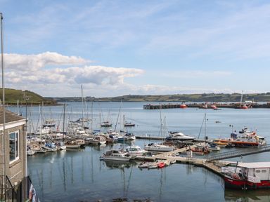 A marina with multiple sailboats and yachts docked and a view of distant hills at 16 Arwenack Street in Falmouth
