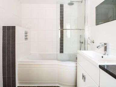 A bathroom with a white bathtub a shower with glass door and a white sink with a faucet at Keepers Cottage in Beeston near Dereham