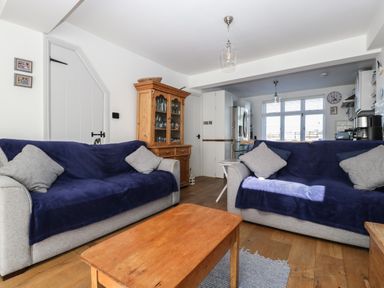 A living room with two sofas covered in blue throws and a wooden cabinet in the corner at Ferriwais in Appledore