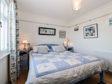 A bedroom with a double bed bedside tables lamps and framed pictures on the wall at Ferriwais in Appledore