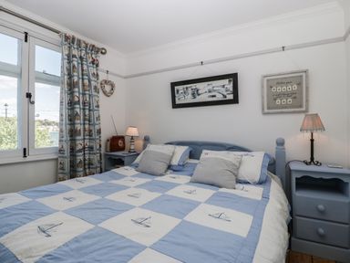 A bedroom with a blue and white bedspread and two bedside tables in Ferriwais Appledore