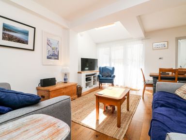 A living room with sofas a wooden coffee table a blue armchair a television and framed pictures on the wall at Ferriwais in Appledore