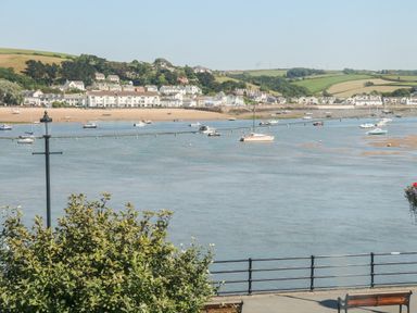 A view of a river with boats moored and houses on the far shore with hills in the background at Ferriwais in Appledore