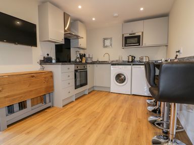 A kitchen with appliances washing machine oven and bar stools at The Granary in Helland near Bodmin