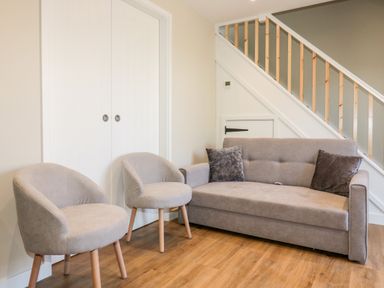 A sitting area with two armchairs and a sofa under a staircase at The Granary in Helland near Bodmin