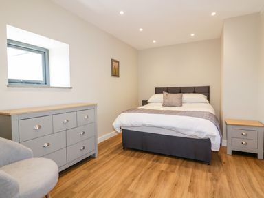 A bedroom with a bed dresser armchair and bedside table at The Granary in Helland near Bodmin