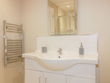 A bathroom sink with a mirror above and a chrome towel rack on the wall at The Granary in Helland near Bodmin