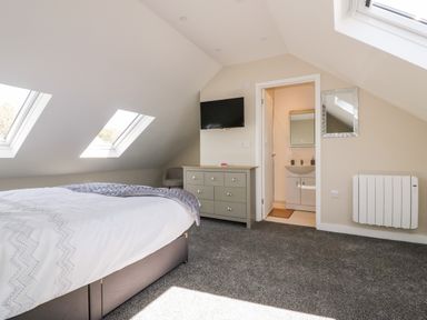 A bedroom with a bed dresser television and doorway to bathroom at The Granary in Helland near Bodmin