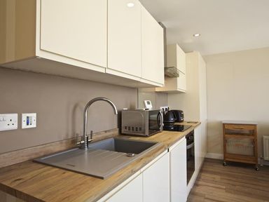 A kitchen with a sink a microwave a kettle and a toaster on wooden countertops at Crowthers in Dartmouth