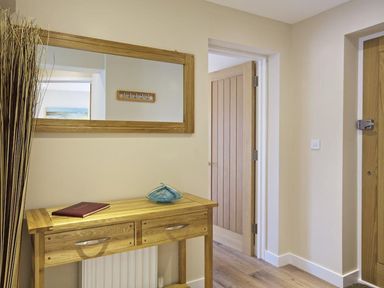 A hallway with a wooden console table and a large mirror above at Crowthers in Dartmouth
